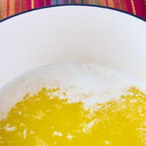 Easy Homemade Ghee Butter cooking in a dutch oven. There is foam beginning to come to the surface.