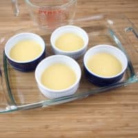 Sweet & Creamy Chai Pudding - Pouring the steeped cream into four ramekins in a baking dish.