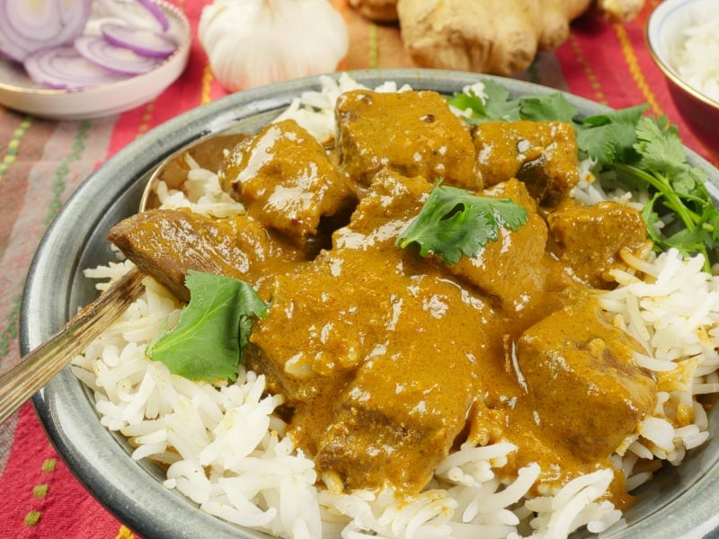 Coconut Lamb Curry (Madras Curry) Served on a bed of fluffy basmati rice, garnished with fresh cilantro leaves.