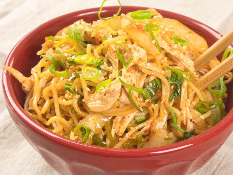 20-Minute Sichuan Noodles served up in a red bowl with chopsticks.