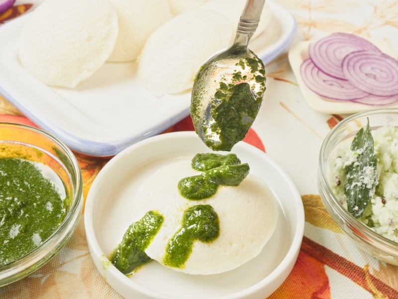 Homemade Idli Recipe Served with dribbles of cilantro chutney.