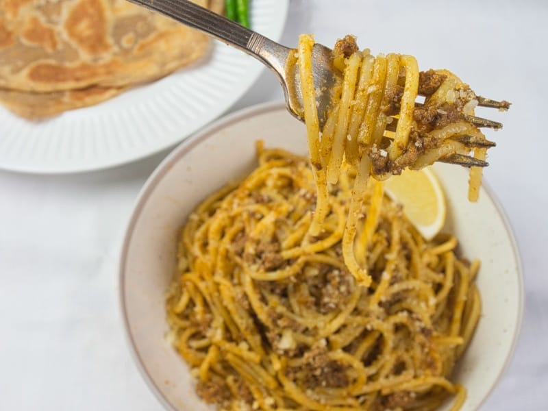 Indian Spaghetti Bolognese a bowl full of bolognese and a fork twirled full of perfectly coated pasta