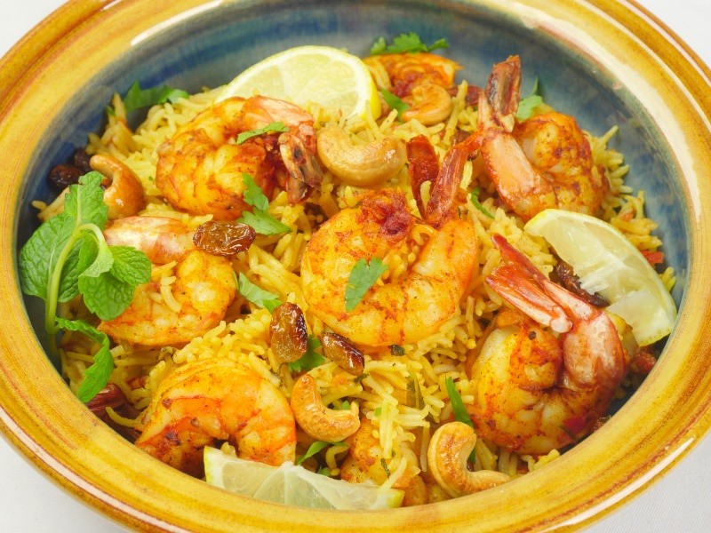 Instant Pot Shrimp Biryani (Kerala-StyInstant Pot Shrimp Biryani (Kerala-Style) Shrimp biryani ready to be served in a pretty pot dressed with slices of lemon, topped with toasted cashews and raisins, and a dusting of fresh herbs.