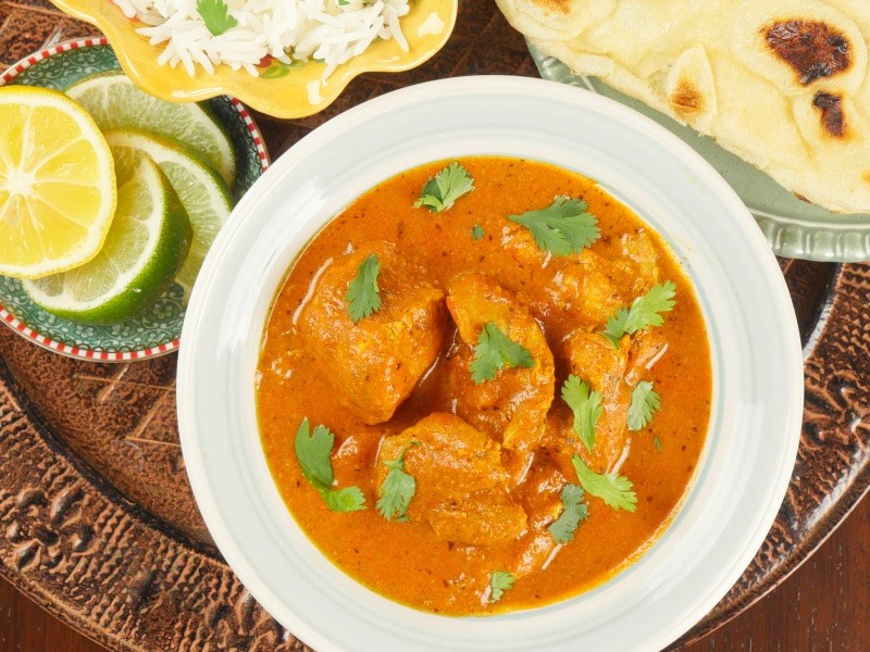 Instant Pot Chicken Tikka Masala Served with a side of paratha, a flutter of cilantro leaves, and wedges of lime.