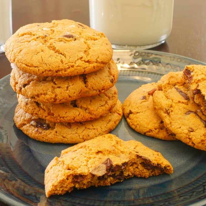 Cookies stacked on a plate with a cold glass of milk.