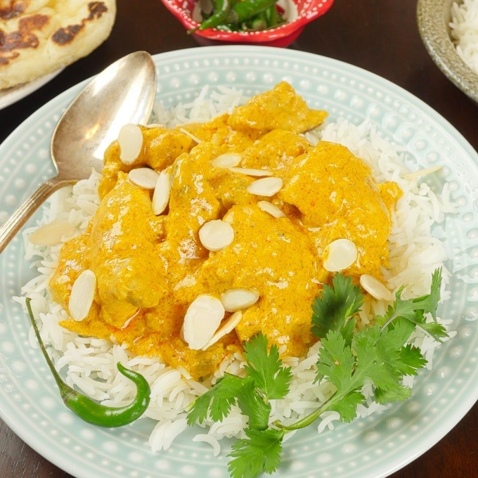Shahi chicken korma served on a bed of rice and garnished with cilantro.