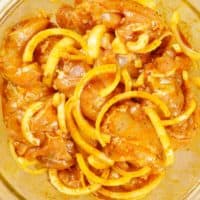 Chicken and onion slices marinading in spices, oil, and lemon juice.