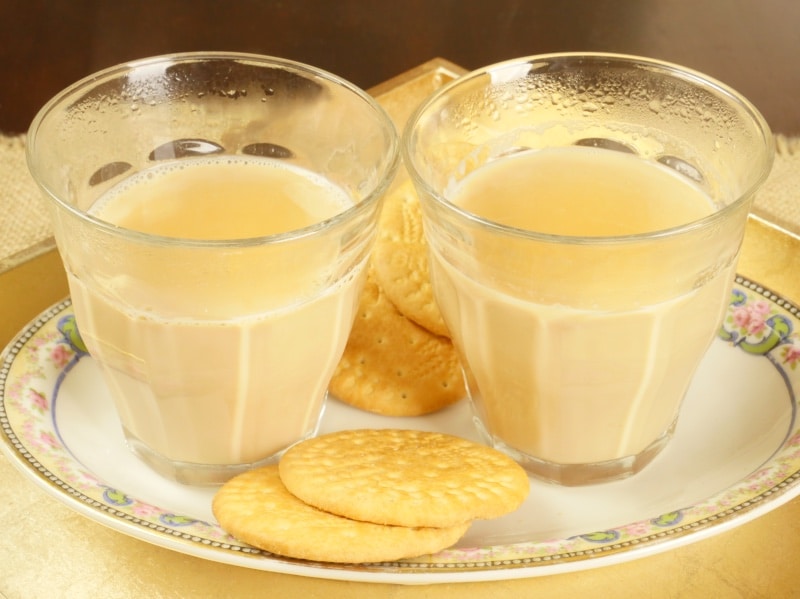 Alonna’s Chai Recipe - Two cups of chai served with Marie biscuits on a pretty plate.