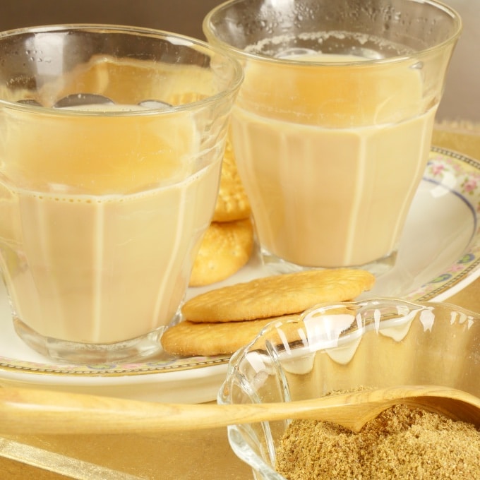 Two cups of chai served with Marie biscuits on a pretty plate.