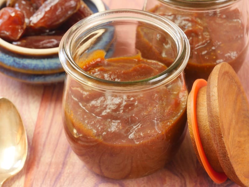 Tangy Tamarind Date Chutney Stored in a pretty tulip-shaped weck jar with a wooden lid and a side bowl of whole dates.