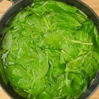 Blanching the spinach in a pot of boiling waater.