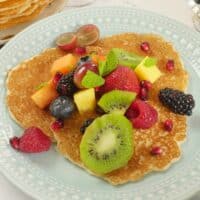 Three rice pancakes served with fruit salad and a flurry of mint leaves.