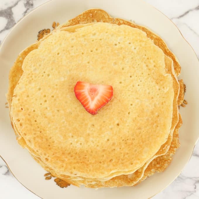Rice Pancakes (Indian-style) A stack of rice pancakes ready for serving topped with some strawberry.