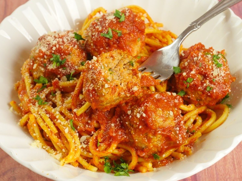 Spaghetti & Curry Meatballs ~ Sauced pasta topped with meatballs garnished with a dusting of parmesan and chopped cilantro.