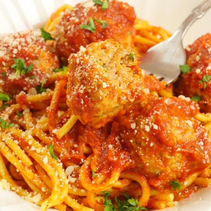 Sauced pasta topped with meatballs garnished with a dusting of parmesan and chopped cilantro.