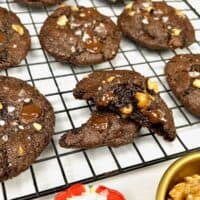 Almond flour chocolate cookies on a cooling rack garnished with flaky salt, chocolate chips and walnuts