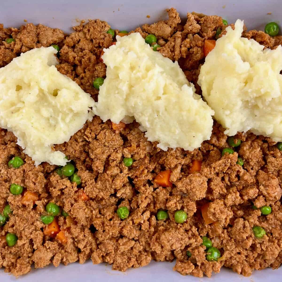 Adding the mashed potato layer dolloped on top of the ground turkey filling for Curried Ground Turkey Shepherd’s Pie