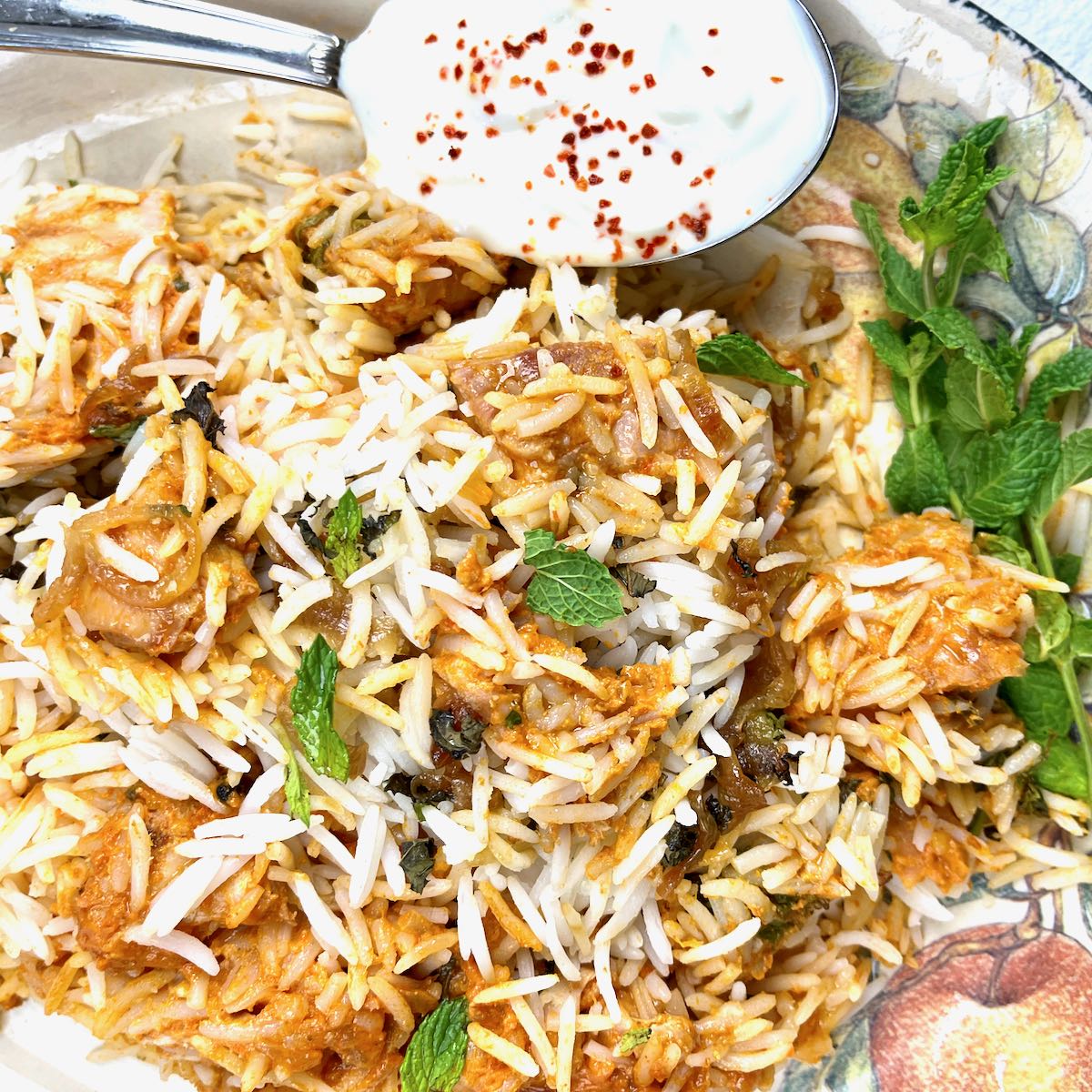 Chicken Tikka Masala Biryani on a serving platter with a side of raita